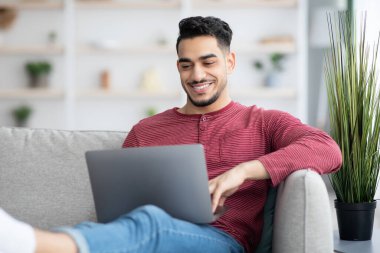 İnternette dizüstü bilgisayar kullanarak sörf yapan yakışıklı bir Arap.