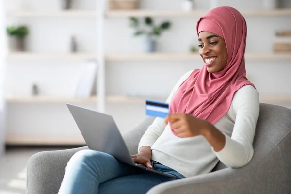 Чорна ісламська жінка купує онлайн з ноутбуком і кредит - карткою вдома — стокове фото