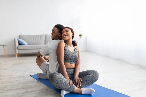 Чорна леді, сидячи спиною до спини зі своїм спортивним хлопцем на позиції лотоса, маючи практику внутрішнього партнера йоги — стокове фото