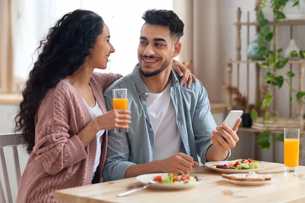 아침 식사중에 스마트폰을 사용하는 행복 한 젊은 아랍 부부 — 스톡 사진