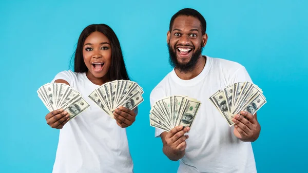 Emocionada pareja afroamericana sosteniendo mucho dinero en dólares —  Fotos de Stock