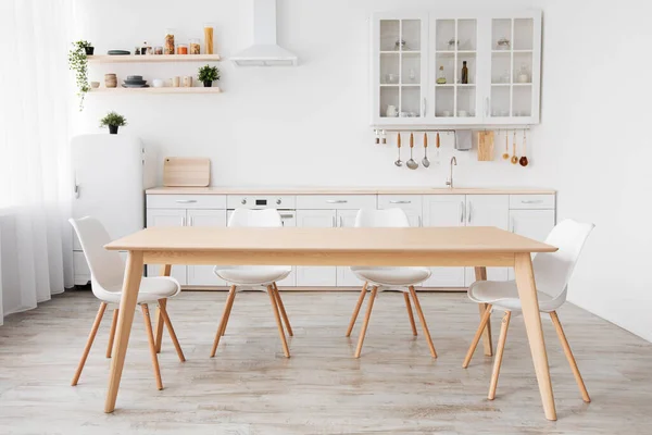 Heldere witte keuken met huishoudelijke artikelen. Modern keukeninterieur, houten tafel en stoelen in de eetkamer — Stockfoto