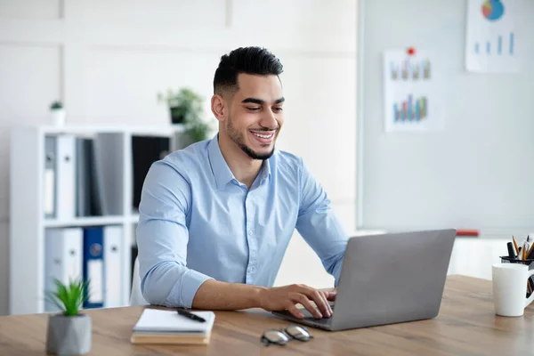 Schöner junger arabischer Geschäftsmann arbeitet mit Laptop an seinem Schreibtisch im Büro — Stockfoto