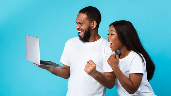 Couple noir excité en utilisant un ordinateur portable célébrant le succès en secouant les poings — Photo