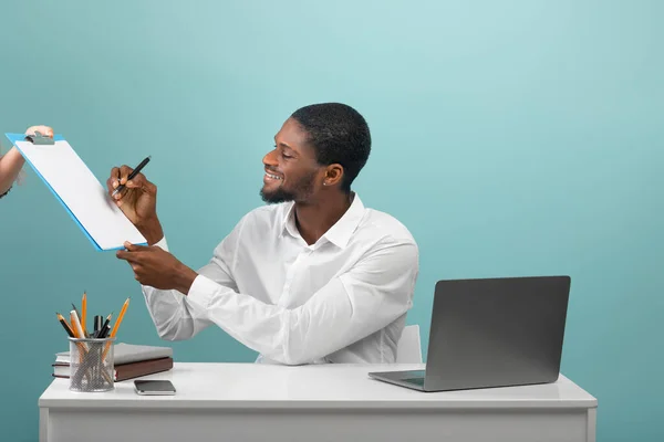 Boldog afro-amerikai üzletember hivatalos kopás aláírási szerződést vagy megállapodást a munkahelyen kék háttér — Stock Fotó
