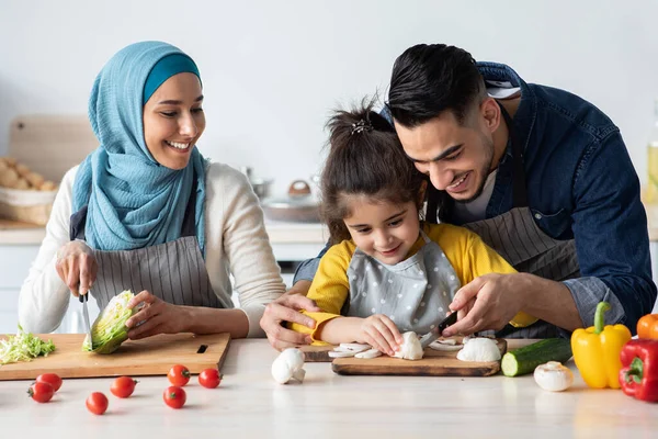 Sevgili Müslüman ebeveynler kızlarına sağlıklı yemek pişirmeyi öğretiyor. — Stok fotoğraf