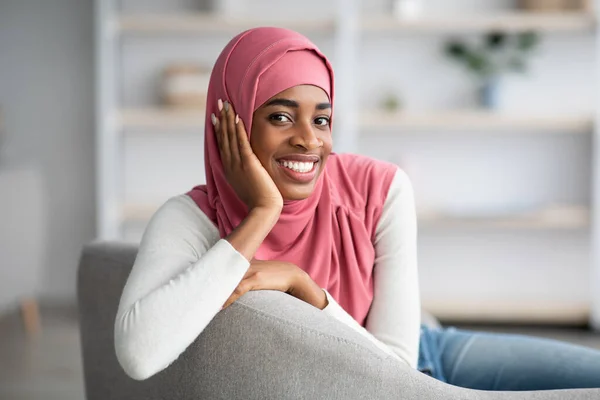 Portret pięknej uśmiechniętej czarnej islamskiej damy w hidżabie relaks na kanapie — Zdjęcie stockowe