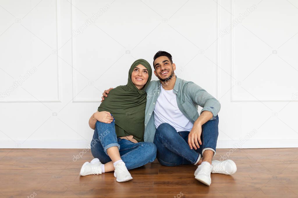 Happy muslim man and woman looking up at home