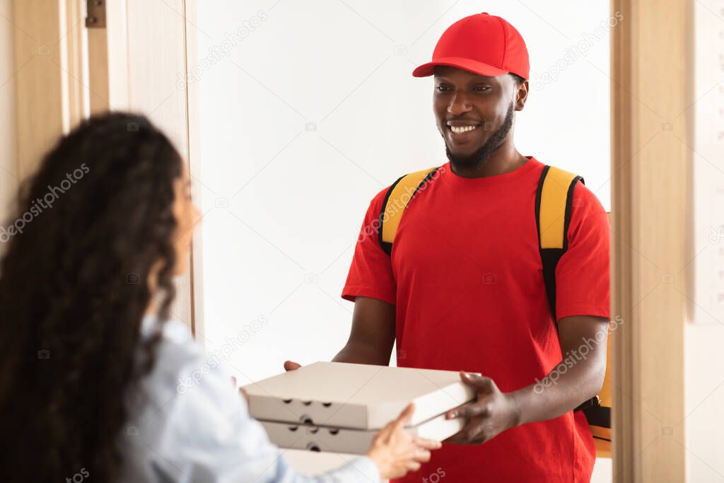 Black delivery man holding and giving pizza boxes