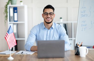 Erkek yabancı diller öğretmeni evde dizüstü bilgisayar kullanarak İngilizce öğretiyor.