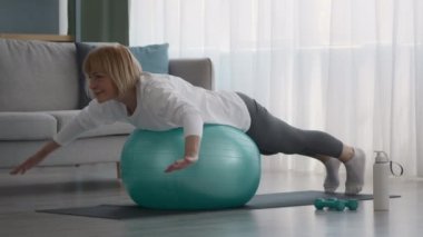 Yaşlı kadın, İsviçre Balosu üzerine egzersiz yapıyor. Evde çalışıyor.