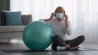 Evde Fitball 'un yanında oturan kıdemli bayan maske takıyor.