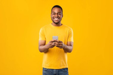 Sarı Arkaplanda Duran Telefonu Kullanan Mutlu Afrikalı Amerikalı Adam