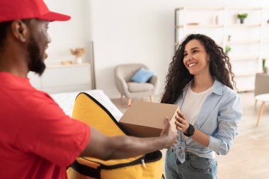 Siyah teslimatçı termal sırt çantasından kutuyu alıyor.