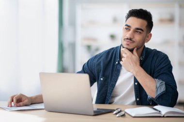 Ofiste oturan hayalperest genç adam, fotokopi odasına bakıyor.