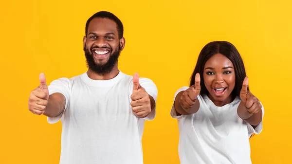 Emocionado casal afro-americano gesticulando polegares para cima e sorrindo — Fotografia de Stock
