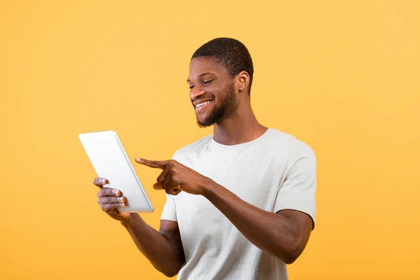 Afrykański bloger męski korzystający z tabletu cyfrowego, surfing w Internecie, odizolowany na żółtym tle, ujęcie studyjne — Zdjęcie stockowe