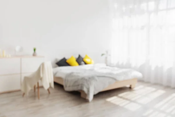 Cama de casal com almofadas amarelas e pretas, cobertor, móveis com plantas em vasos — Fotografia de Stock