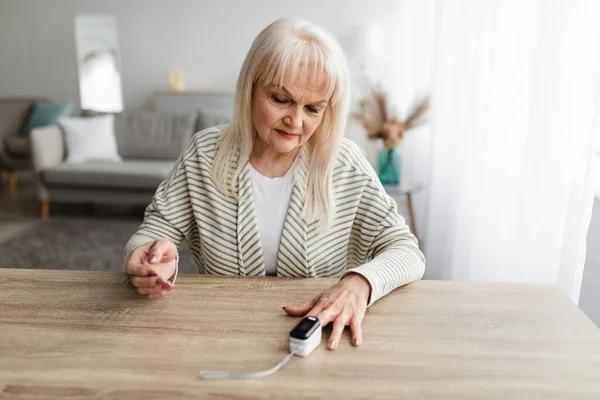 Senior mulher usando oxímetro em casa. Conceito de Atenção à Saúde — Fotografia de Stock