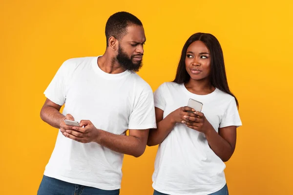 Homem preto verificando sua namorada telefone inteligente — Fotografia de Stock