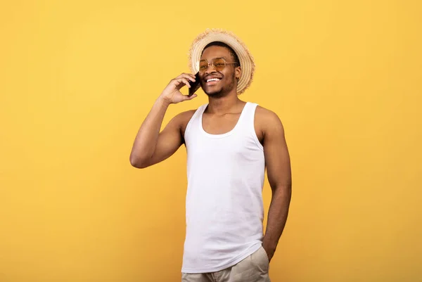 Feliz hombre negro en ropa de verano haciendo llamada en el teléfono celular, tener conversación sobre fondo amarillo estudio —  Fotos de Stock