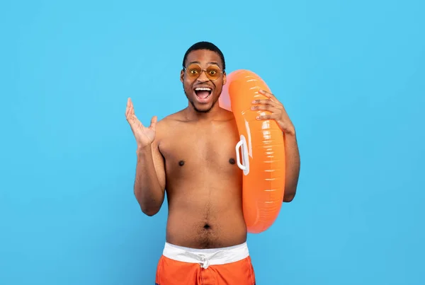 Mayolu duygusal siyahi adam elinde şişme yüzük, bağırıyor, harika bir yaz tatili geçiriyor, mavi arka plan. — Stok fotoğraf