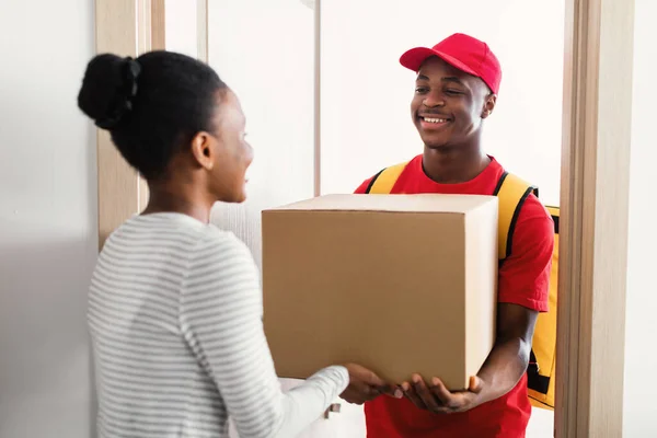 African American Courier Giving Box für eine Frau, die in der Tür steht — Stockfoto