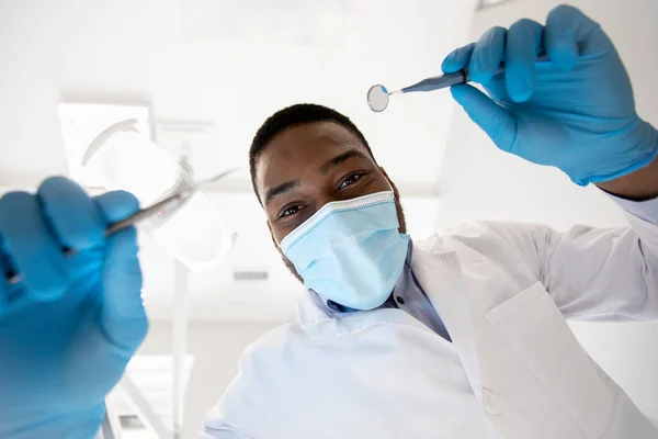 Low angle view van zwarte tandarts controleren patiënten tanden met tandheelkundig gereedschap — Stockfoto