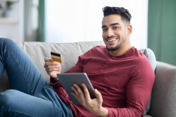 Hombre árabe feliz con tarjeta de crédito y pad shopping en línea —  Fotos de Stock