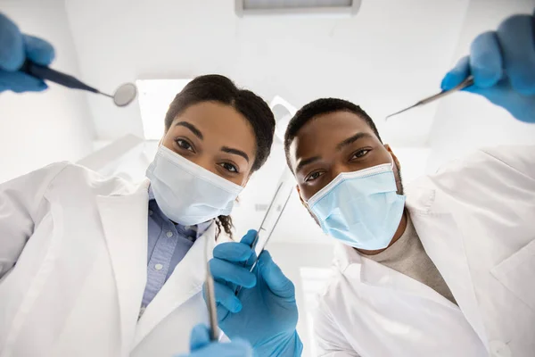 Stomatologische behandeling. Zwarte tandarts en arts assistent controleren patiënten tanden, lage hoek — Stockfoto
