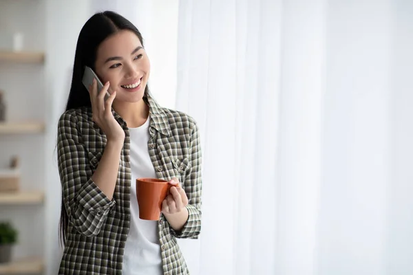 Gelukkig aziatische vrouw met mok hebben telefoon gesprek — Stockfoto