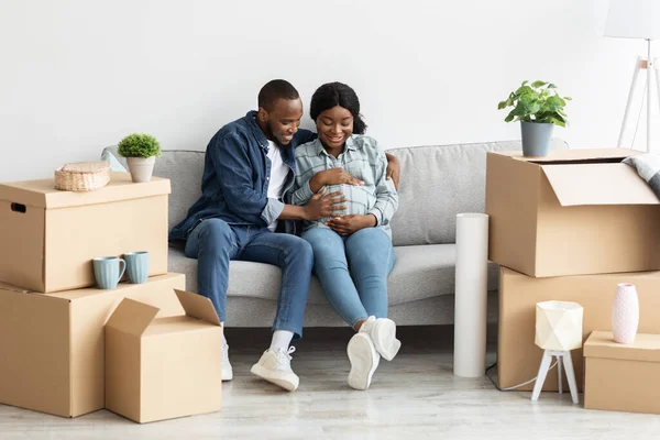 새로운 보금자리에서 소파에 앉아 즐거운 임신 한 아프리카 계 미국인 부부 — 스톡 사진