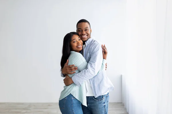 Loving african american couple standing in their house, hugging and smiling, being happy of buying own lodging — Stock Photo, Image