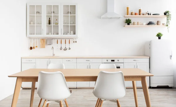 Modern design skandináv konyha. Fehér konyhabútor és étkezőasztal székekkel, evőeszközökkel és konyhai eszközökkel — Stock Fotó