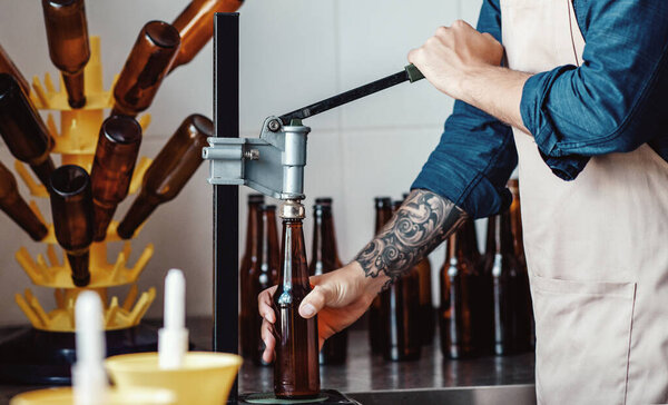 Работник или владелец пивоваренного завода использует оборудование для производства напитков на заводе