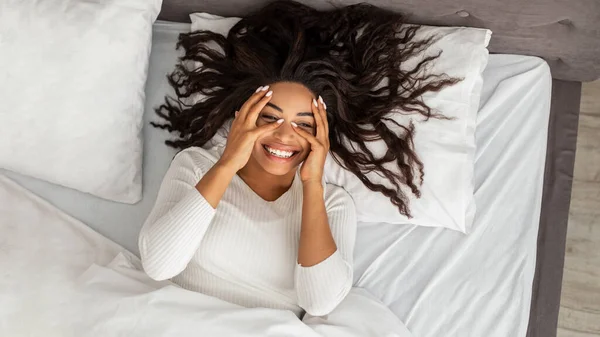 Счастливая молодая афроамериканка лежит в постели — стоковое фото