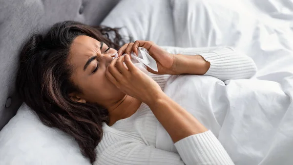 Черная женщина с сморщенным носом лежит в постели — стоковое фото