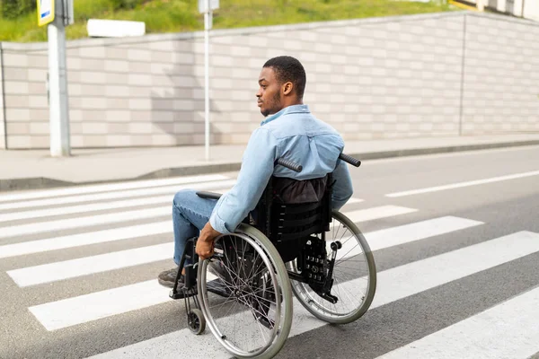 Fiatal, mozgássérült fekete férfi tolószékben, járdával a szabadban. Életminőség és értékvesztés fogalma — Stock Fotó