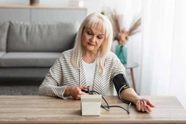 Mulher sênior medindo a pressão arterial em casa — Fotografia de Stock