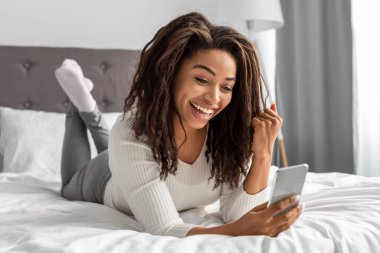 Heyecanlı siyahi kadın telefonda yumruğunu sallıyor.