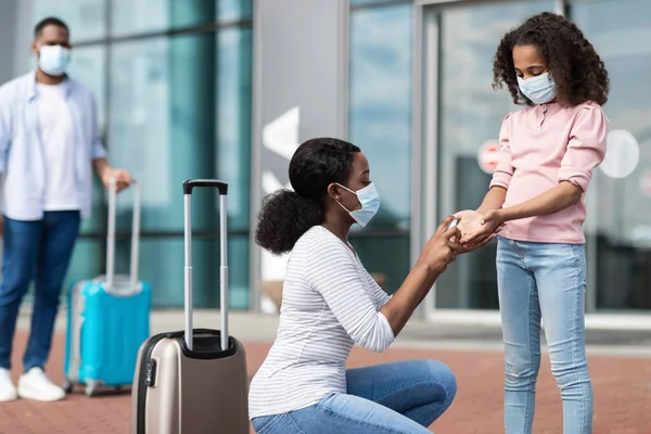 Familia negra viajando con un niño, usando desinfectante —  Fotos de Stock