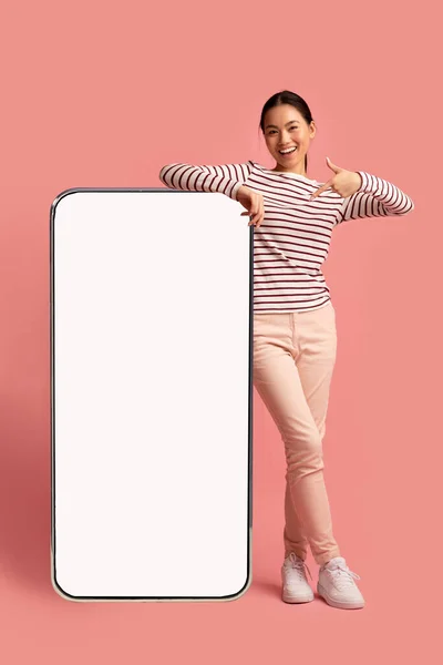Joyeuse asiatique dame penché et pointant vers Big Smartphone avec écran blanc — Photo