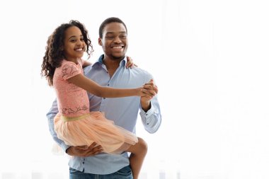 Neşeli Afro-Amerikan babası ve çocuğu beyaz üzerinde dans ediyor.