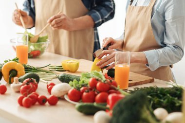 Mutlu çift evde birlikte lezzetli bir akşam yemeği hazırlıyor aile yemeği için, yemek pişirme sürecinin tadını çıkarıyor.
