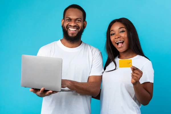 Família negra usando computador e cartão de crédito na parede do estúdio — Fotografia de Stock