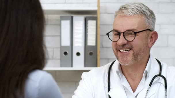 Alegre doctor hablando con paciente femenina durante cita médica en interiores — Vídeos de Stock