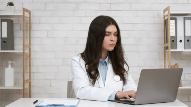 Female Physician Nodding Head To Laptop Consulting Patient Online Indoor — Αρχείο Βίντεο