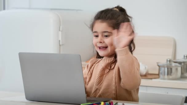 Pequena menina árabe acenando Olá para laptop na cozinha moderna — Vídeo de Stock