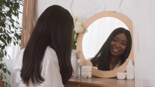 Afroamericano donna spazzolatura capelli seduta vicino specchio a casa — Video Stock