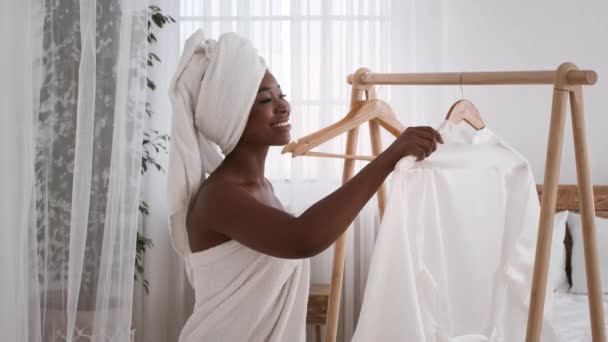 Африканська леді одягається взявши одяг з одягу рейки в приміщенні — стокове відео